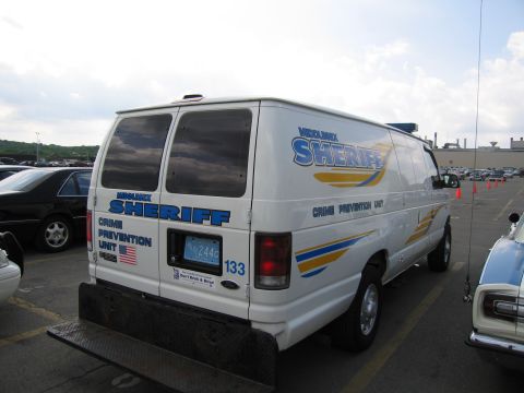 1991 Ford LTD Crown Victoria - Rear three-quarter view of a white Ford Sheriff Crime Prevention Unit cargo van numbered 133 in a parking lot.