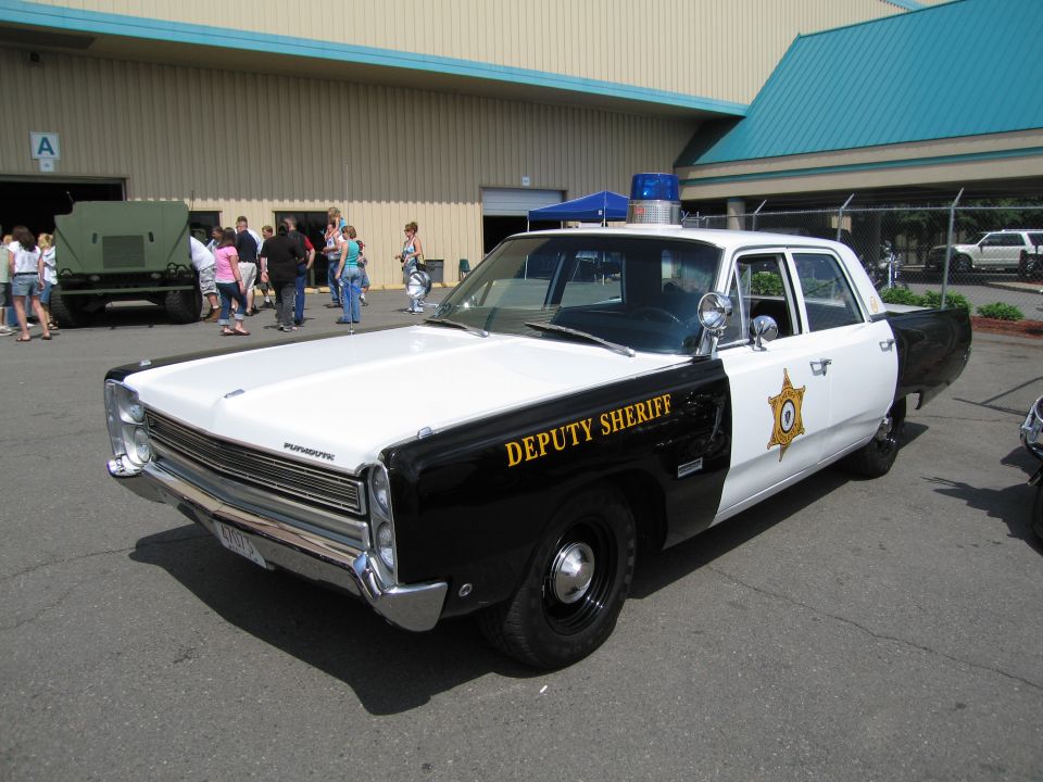 Black and white Plymouth Deputy Sheriff sedan at a car show