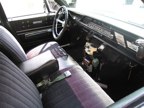 1991 Ford LTD Crown Victoria - cloth bench-seat interior of a classic sedan fitted with vintage police radio and microphone equipment on the floor hump.