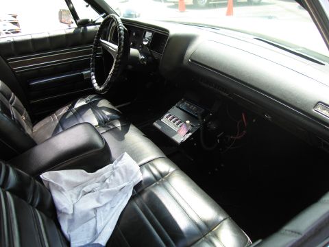 1991 Ford LTD Crown Victoria - black vinyl interior of a classic car with under-dash electronic gear and a white cloth draped over the front seat.