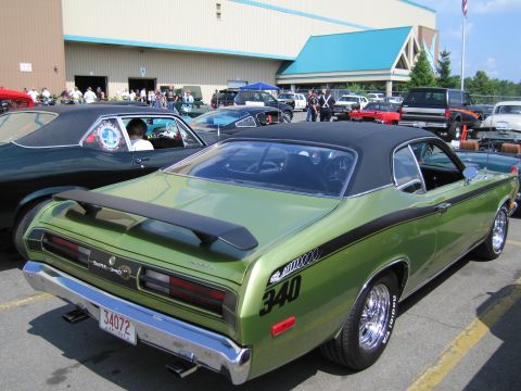 1991 Ford LTD Crown Victoria - green Duster 340 with black graphics is parked beside other classic cars in front of a show building.