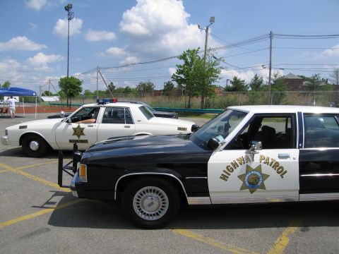 1991 Ford LTD Crown Victoria - black-and-white Ford sedan marked Highway Patrol sits next to a white sheriff cruiser in a parking lot.