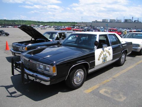 1991 Ford LTD Crown Victoria - black-and-white Ford LTD marked Highway Patrol sits with hood open among classic cars at a show.