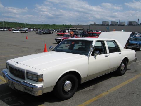1991 Ford LTD Crown Victoria - white Chevrolet Caprice sedan with its trunk open is parked among rows of cars at an outdoor show.