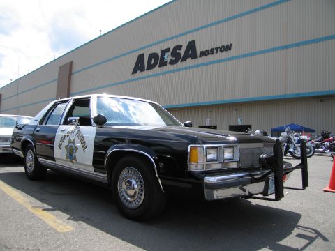 1991 Ford LTD Crown Victoria - Front three-quarter view of a black-and-white police sedan marked Highway Patrol parked outside the ADESA Boston building.