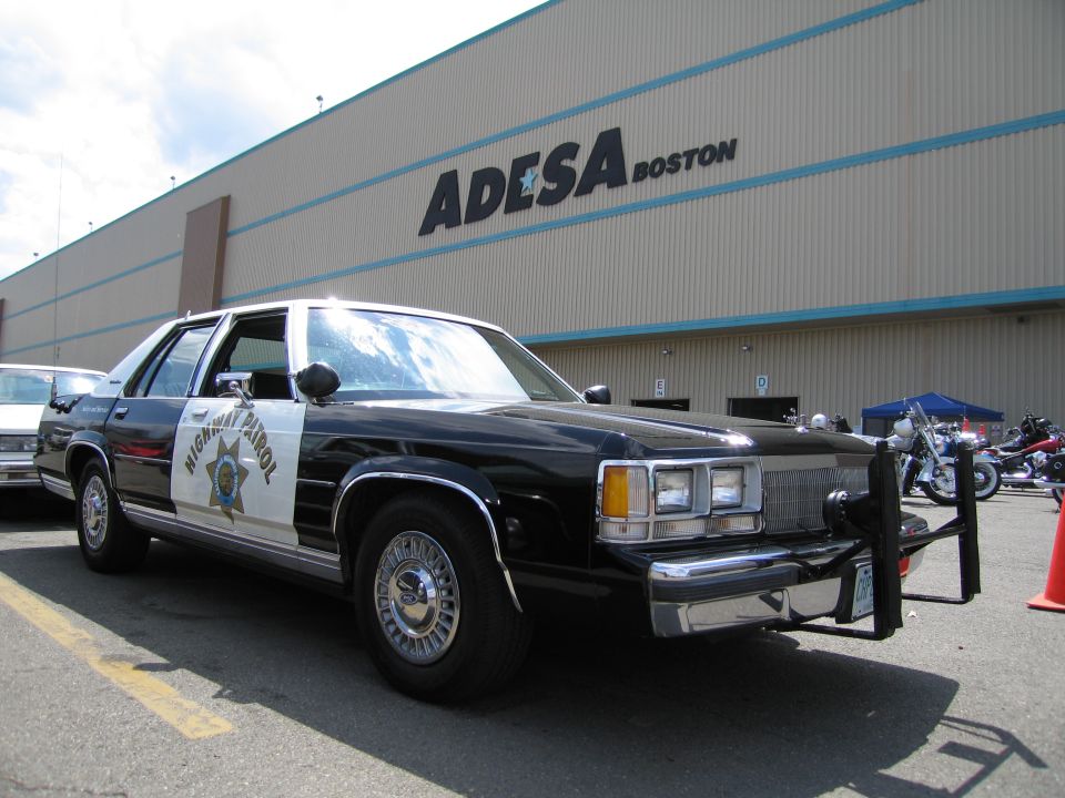 Front three-quarter view of black-and-white Highway Patrol sedan at ADESA Boston