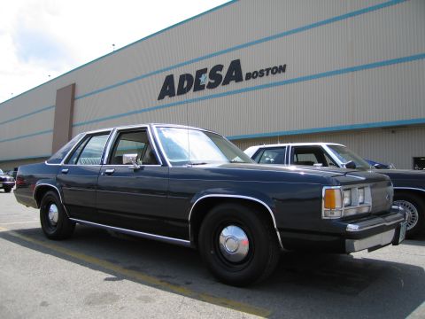 1991 Ford LTD Crown Victoria - dark blue full-size four-door sedan with whitewall-style hubcaps parked outside the ADESA Boston building.