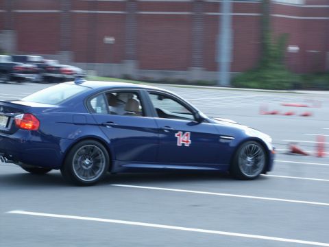 2001 Mercury Grand Marquis - Motion photograph of a blue BMW M sedan numbered 14 driving an autocross course past a brick wall.