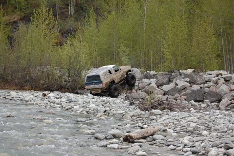 1978 Ford Bronco - A 1978 Ford Bronco navigates a challenging rocky terrain beside a flowing stream.