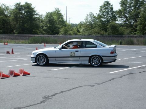 2001 Mercury Grand Marquis - Autocross action photo of a silver BMW E36 coupe, number 33, on a paved course lined with traffic cones.