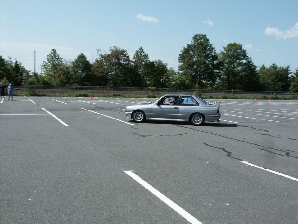Silver BMW E30 M3 on an autocross course under a blue sky