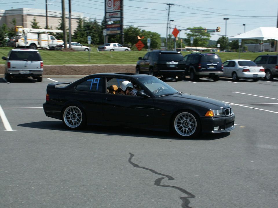 Black BMW E36 coupe number 79 cornering at an autocross