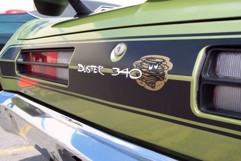 2001 Ford Crown Victoria - A close-up of the rear of a lime green classic car shows a black stripe with gold pinstripes and a "DUSTER 340" emblem with a cartoon torna…
