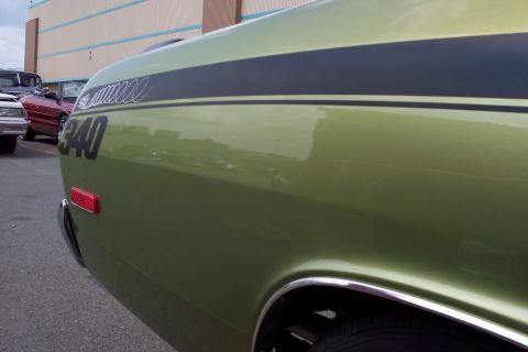 2001 Ford Crown Victoria - Close-up side view of a vintage green muscle car with black racing stripes and a "340" decal. The car has a chrome trim around the wheel we…
