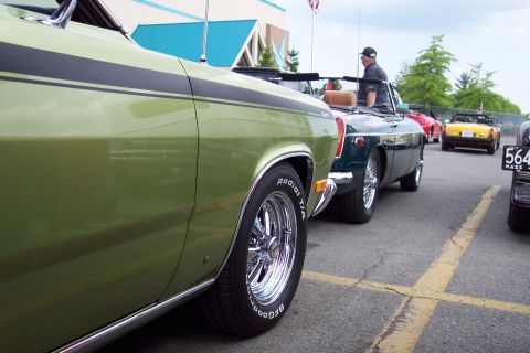 2001 Ford Crown Victoria - A close-up, side-profile view of a light green classic convertible with a black stripe along the side. The car is parked on asphalt with ye…