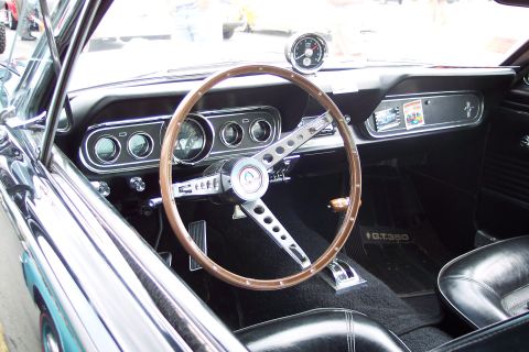 2001 Ford Crown Victoria - The interior of a 1965 Ford Mustang GT350 features a classic wood-rimmed steering wheel and a dashboard with multiple gauges.