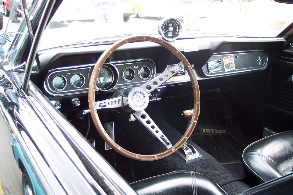 Interior view of a 1965 Ford Mustang GT350 with wood steering wheel and black seats
