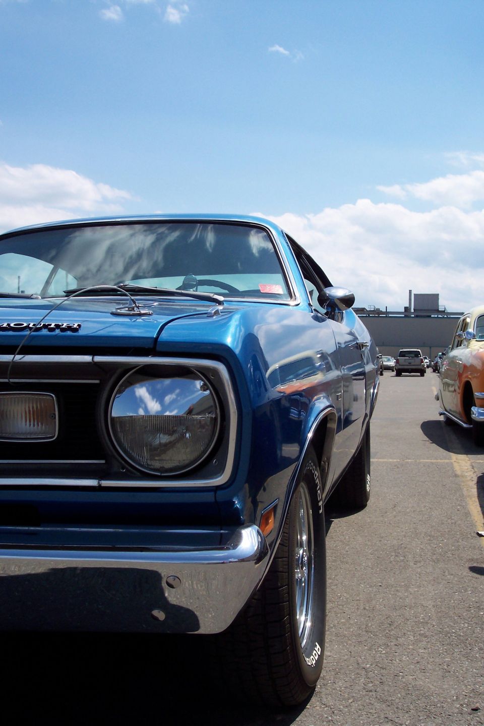 Blue Plymouth Duster with chrome bumper and fender, parked outdoors under a cloudy sky
