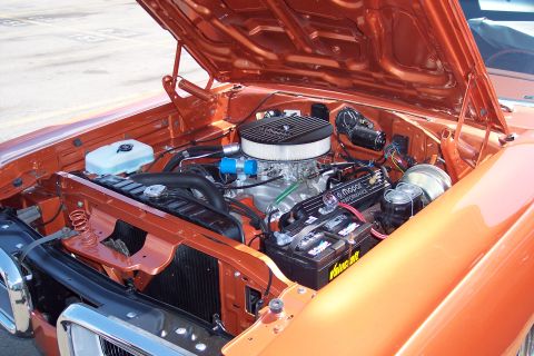 2001 Ford Crown Victoria - The engine bay of an orange classic car is shown with the hood open. Visible components include the air filter, carburetor, Mopar performan…