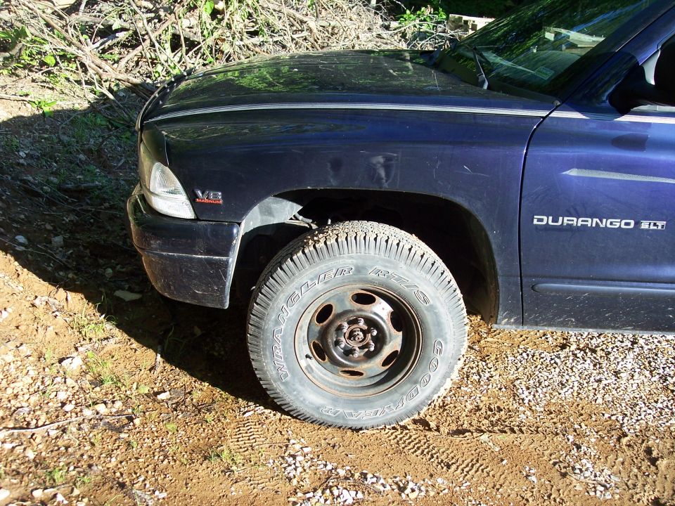 Dark blue SUV front fender and tire on dirt road