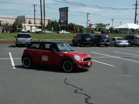 2001 Mercury Grand Marquis - A red Mini Cooper with racing number 172 is parked in a lot with other vehicles and buildings visible.