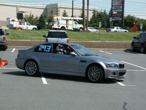 2001 Mercury Grand Marquis - A silver BMW M3 coupe is seen on a paved surface, possibly at an event, with other vehicles and buildings in the background.