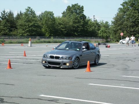 2001 Mercury Grand Marquis - Silver BMW M3 coupe navigates an autocross course on a sunny day, with other vehicles and people in the background.