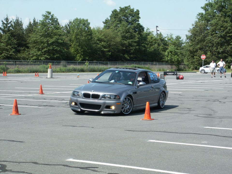 Silver BMW M3 coupe on asphalt course with orange cones. Sunroof open