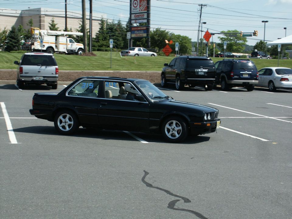 Black coupe in a parking lot, side view
