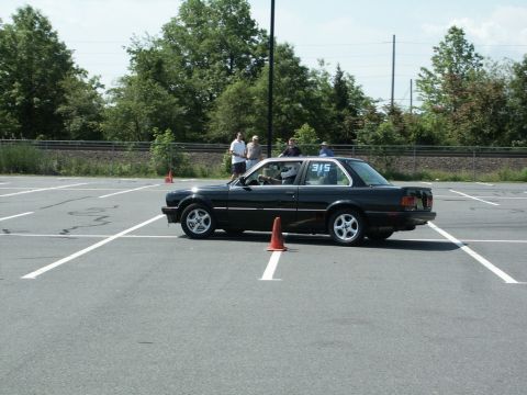 2001 Mercury Grand Marquis - A black BMW E30 coupe is seen participating in an autocross event on a paved lot with orange cones.