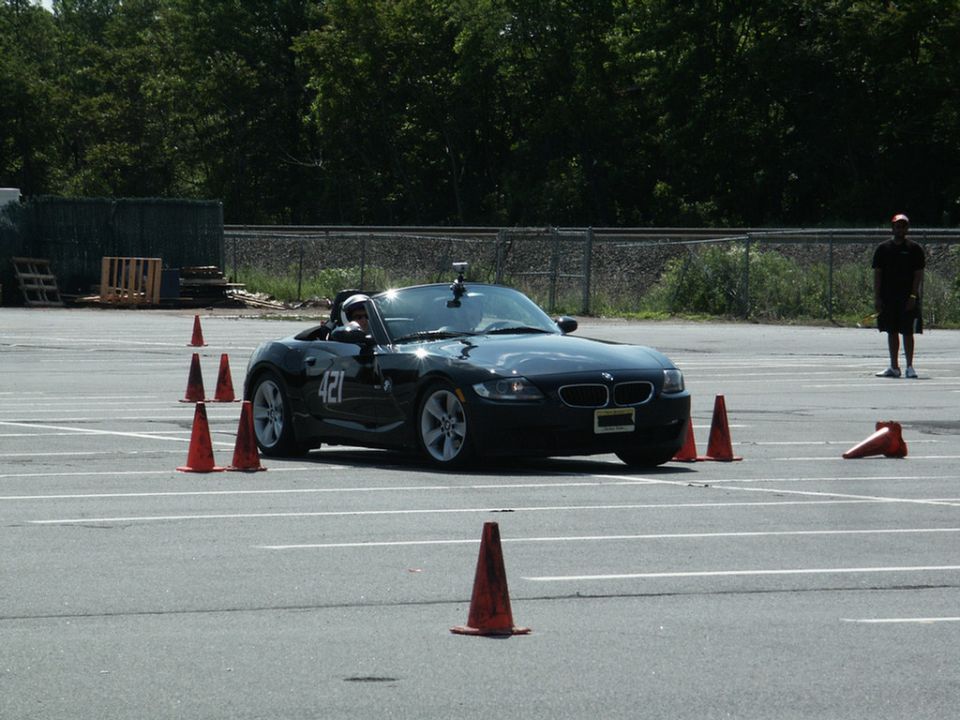 Black BMW convertible with number 421 on the side, navigating an autocross course with orange cones