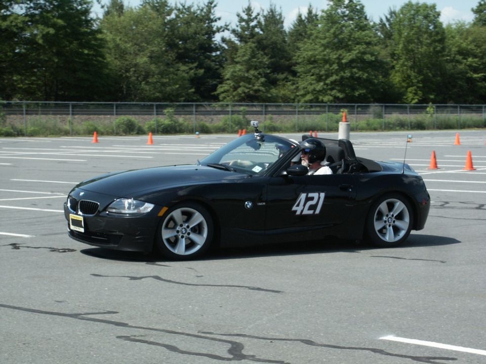 Black convertible sports car with racing number 421 on the side, driver wearing a helmet