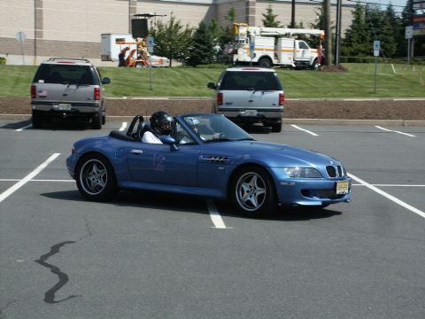 2001 Mercury Grand Marquis - A blue convertible sports car, possibly a BMW Z3, is parked in a lot with other vehicles and a utility truck in the background.