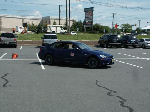 2001 Mercury Grand Marquis - A blue BMW M3 sedan with a large white number 14 on the door runs an autocross course marked by orange cones in a shopping-center parking l…