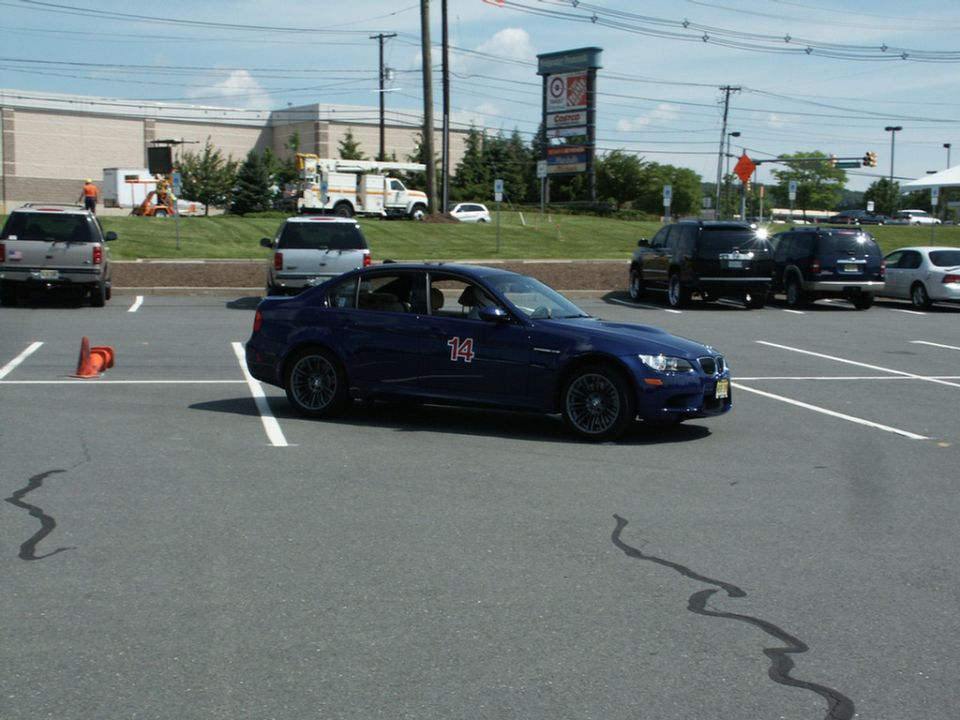 Blue BMW M3 sedan with number 14 running an autocross course in a parking lot