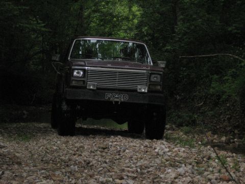 1980 Ford Bronco - This 1980 Ford Bronco is seen from the front, parked on a gravel road surrounded by trees.