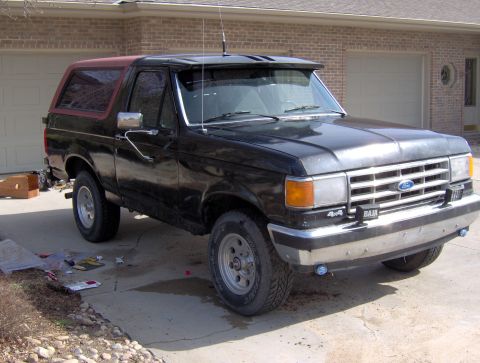 1987 Ford Bronco - This 1987 Ford Bronco features a black body with a contrasting red removable top and a prominent chrome bumper.