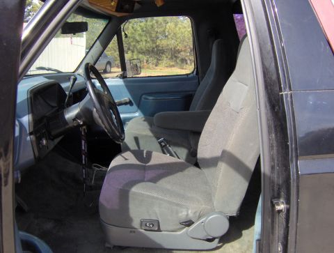 1987 Ford Bronco - The interior of a Ford Bronco is shown, focusing on the driver's side seat and controls.