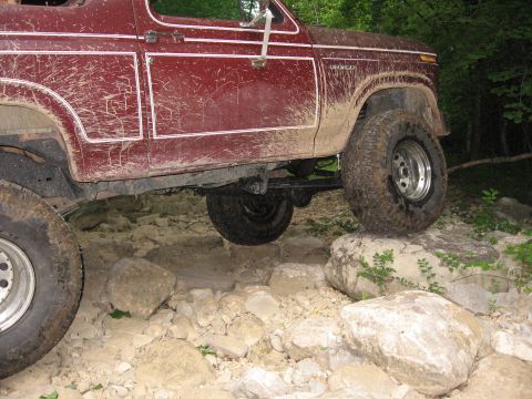 1980 Ford Bronco - This red 1980 Ford Bronco navigates a rocky trail, demonstrating its off-road capabilities.