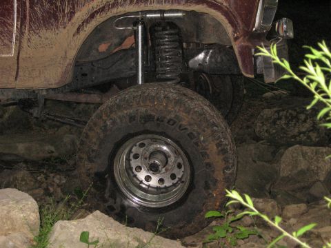 1980 Ford Bronco - This maroon Ford Bronco, likely from the late 1970s, navigates a rocky path with its lifted suspension.