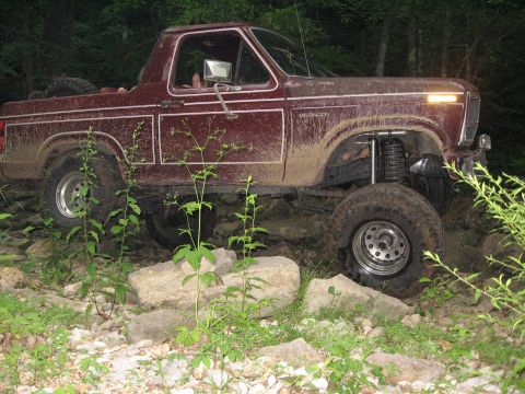 1980 Ford Bronco - This 1980 Ford Bronco is shown off-roading on a rocky trail with mud splattered on its body.