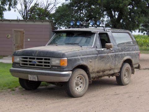 1987 Ford Bronco - This 1987 Ford Bronco is heavily coated in mud, suggesting recent off-road use.