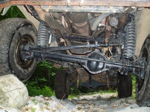 1980 Ford Bronco - Undercarriage view of a modified 4x4 vehicle, likely a Ford Bronco, showing the front suspension, steering linkage, and differential. The v…