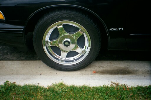 Chrome five-spoke wheel on black Chevrolet with LT1 badge