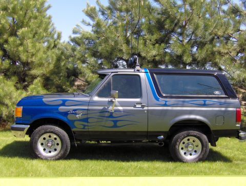 1987 Ford Bronco - 1987 Ford Bronco with custom flame graphics parked on grass.