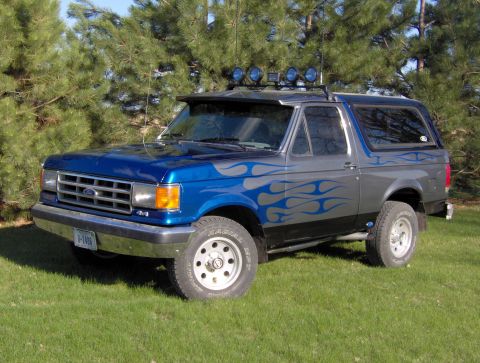 1987 Ford Bronco - This 1987 Ford Bronco features a two-tone paint job with blue flames and auxiliary lights on the roof.