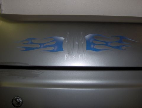 1987 Ford Bronco - A close-up shot shows a custom airbrushed design featuring blue flames and the text "DESIGN" on a silver vehicle panel.