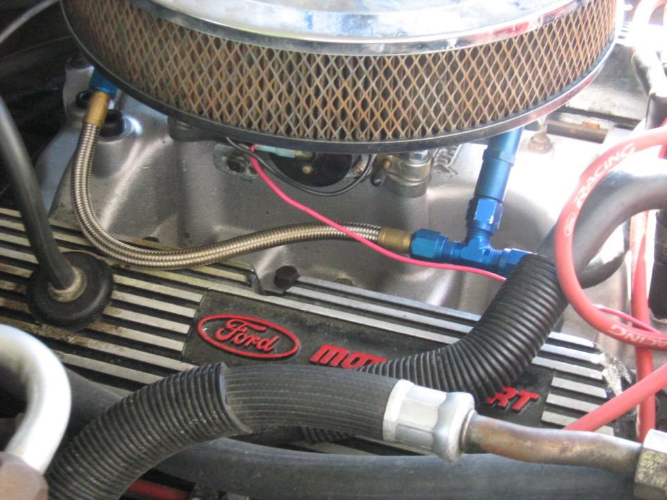 Close-up of a Ford engine bay with braided fuel lines and Ford branding on the valve cover.
