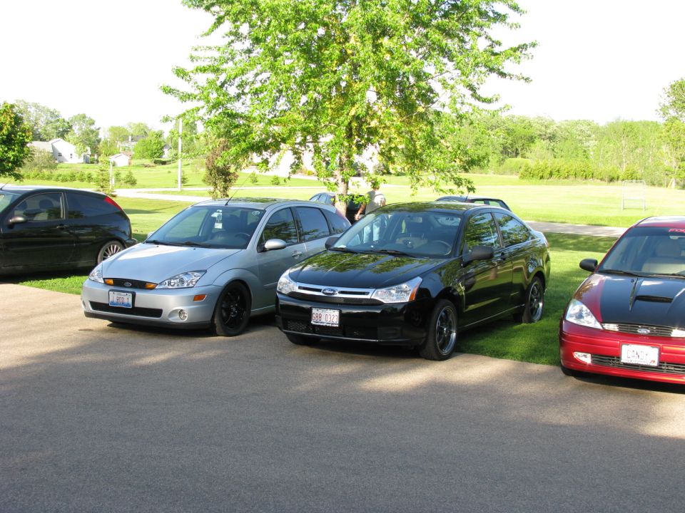 Three Ford Focus cars parked in a line, silver, black, and red.