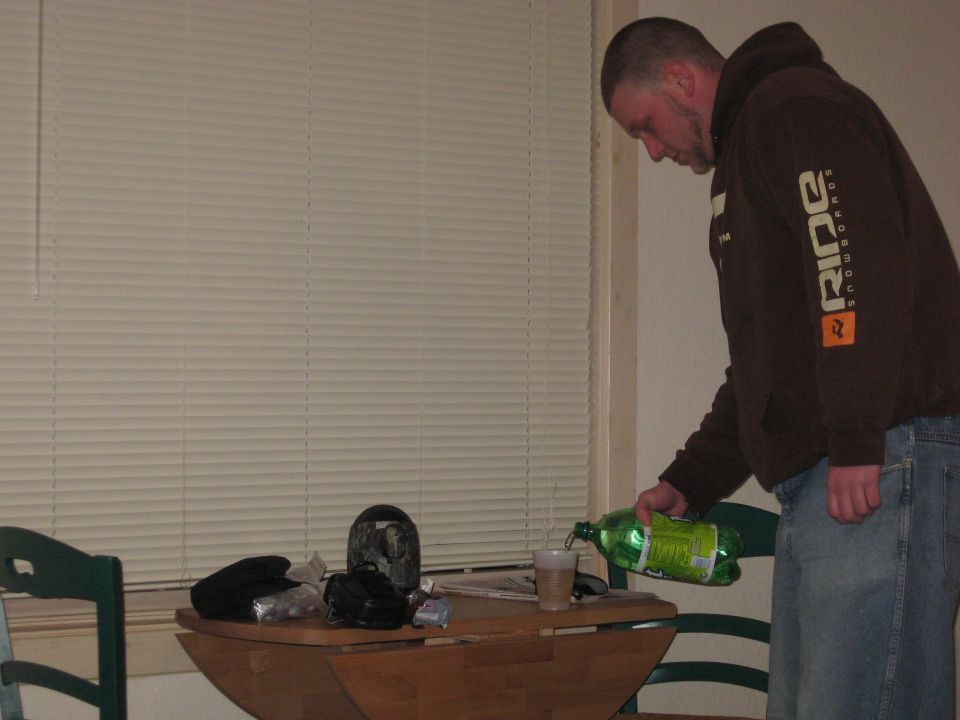 Man pouring drink from bottle into cup on a table.